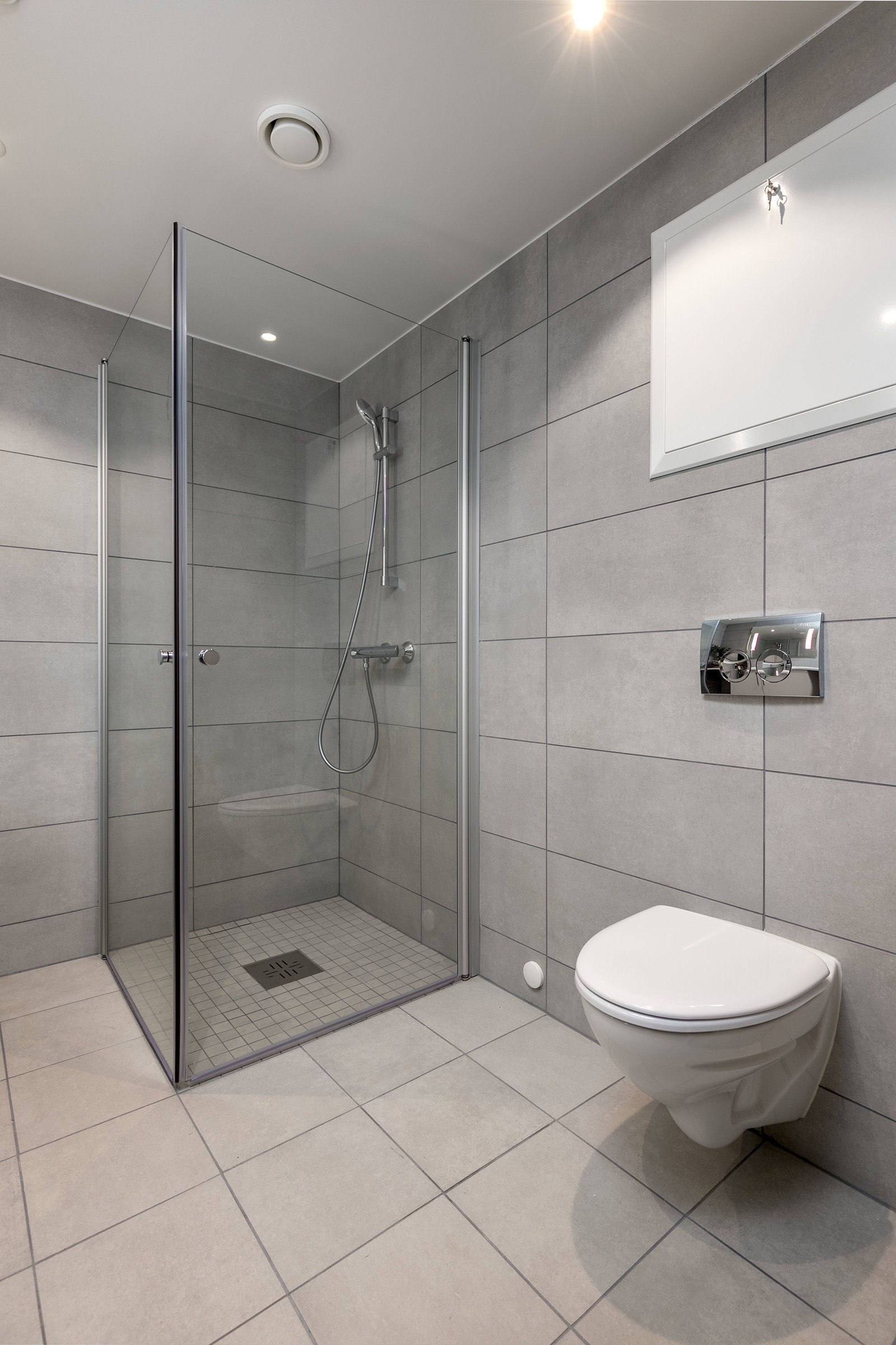 Badet har vegghengt toalett med innbygget sisterne, servant med skapinnredning samt speil med belysning. Galleribilde