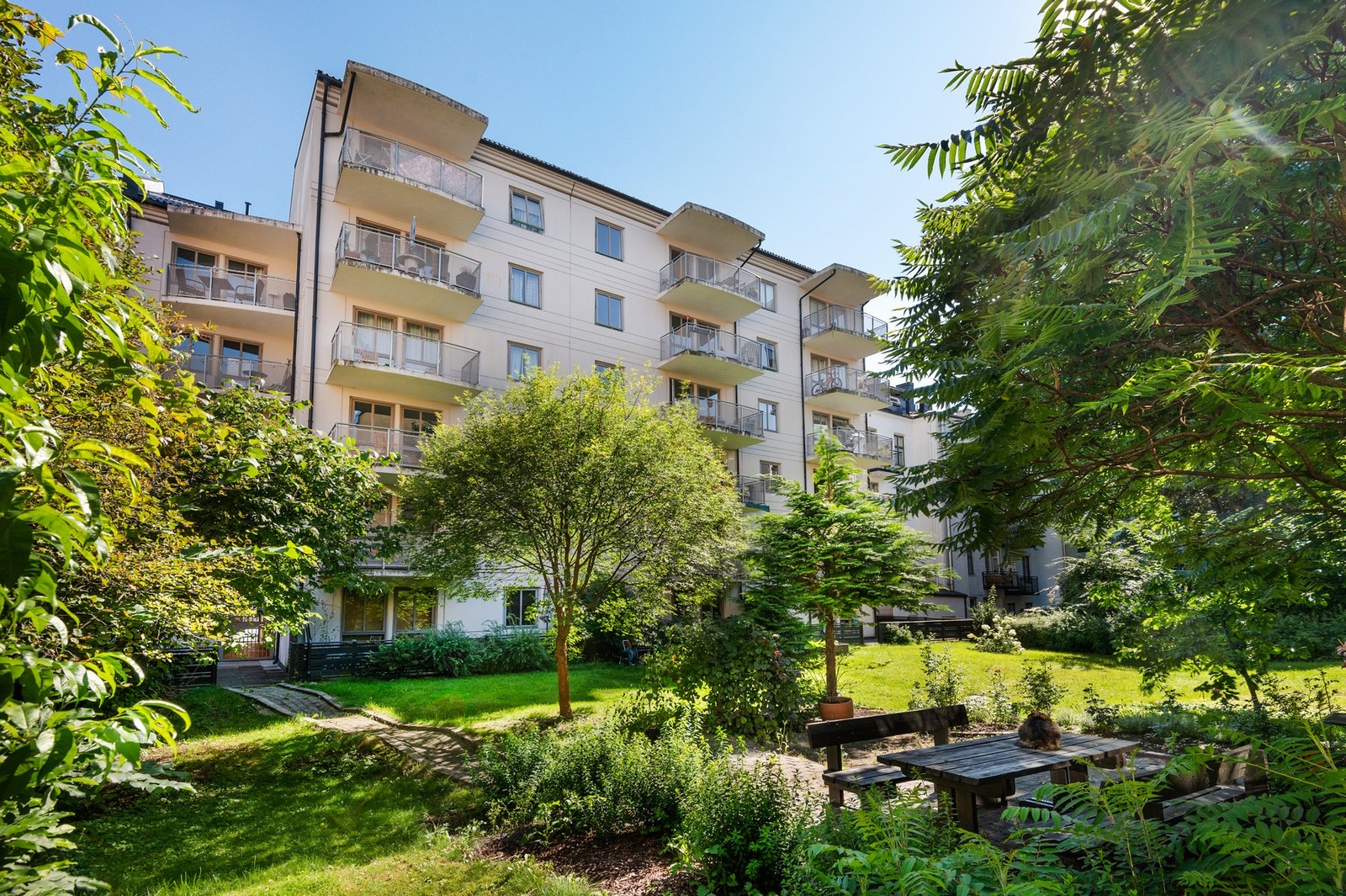 Bakgården er pent opparbeidet med sittebenker, gressplen, beplantning og grill. Galleribilde