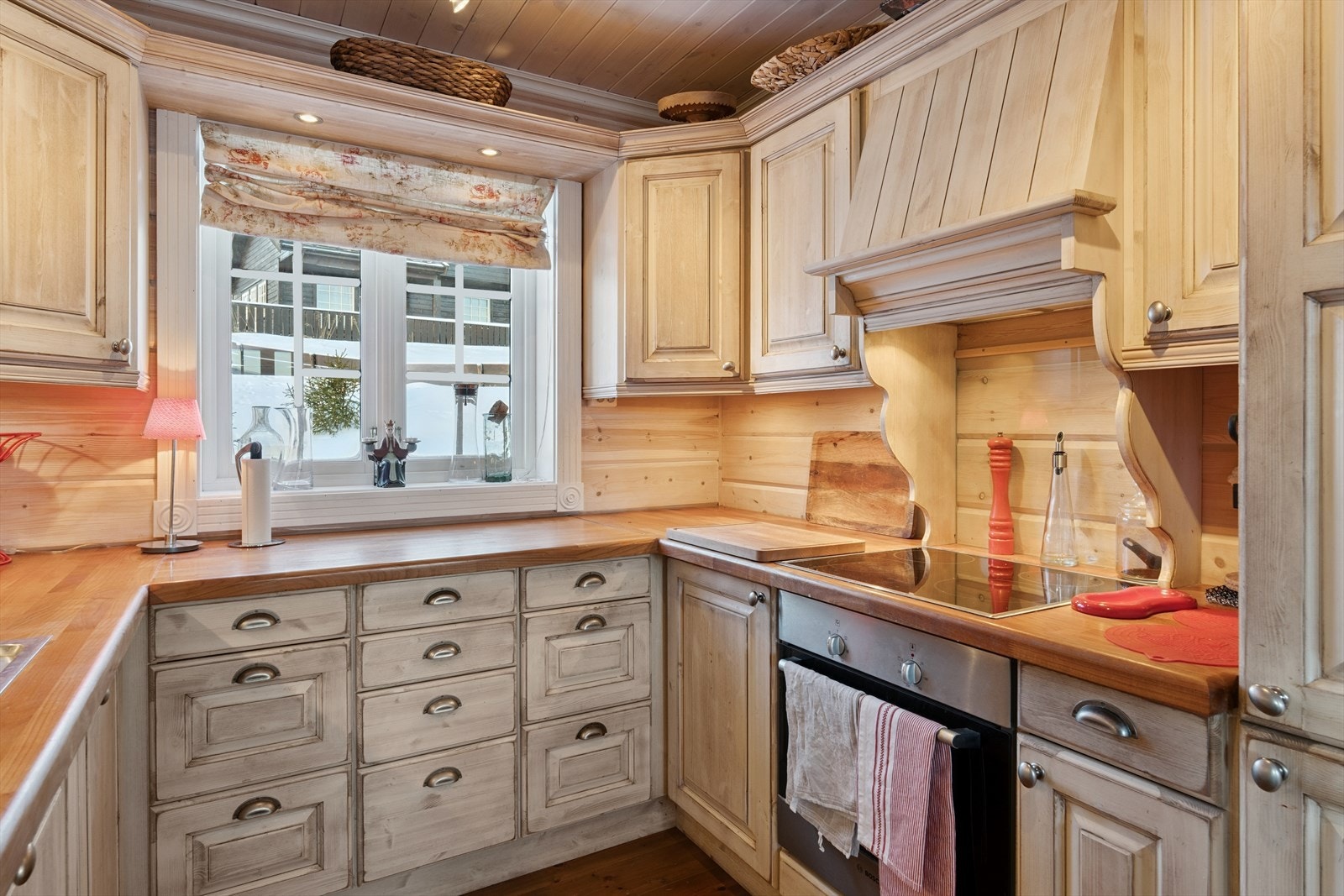 Integrerte hvitevarer med komfyr, koketopp, oppvaskmaskin og kjøle-/fryseskap. Innredningen har også innebygd kjøkkenventilator, og over vinduet er det en hylle med innfelte downlights. Galleribilde