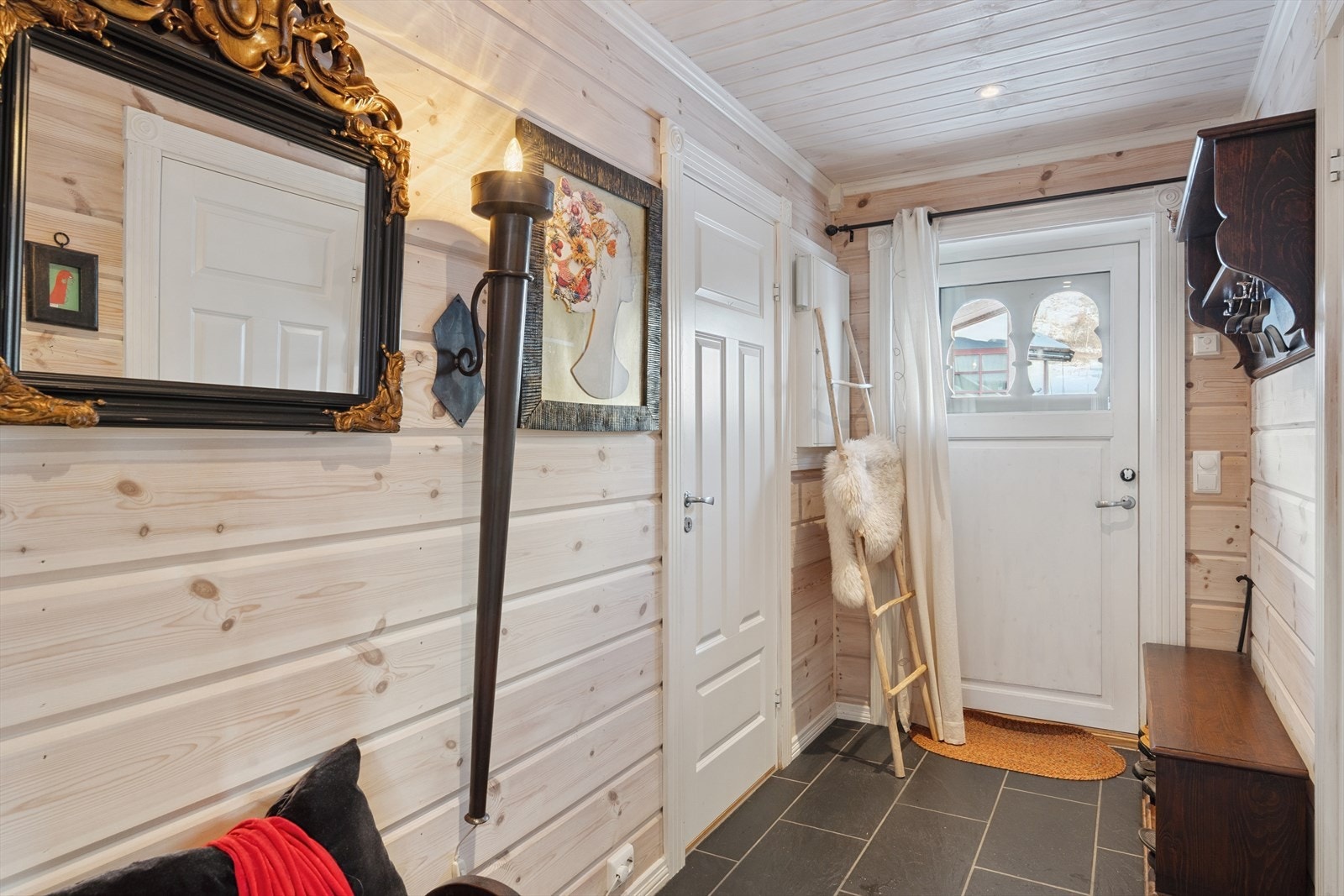 En stilfull inngangsdør med glassfelt ønsker alle velkommen inn i et romslig vindfang. Galleribilde