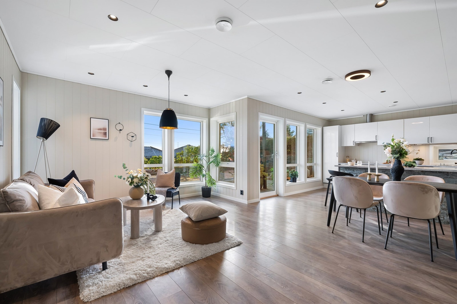 Lys og moderne stue med åpen løsning mot kjøkken og spiseplass og store vindusflater som gir flott romfølelse og godt lysinnslipp Galleribilde