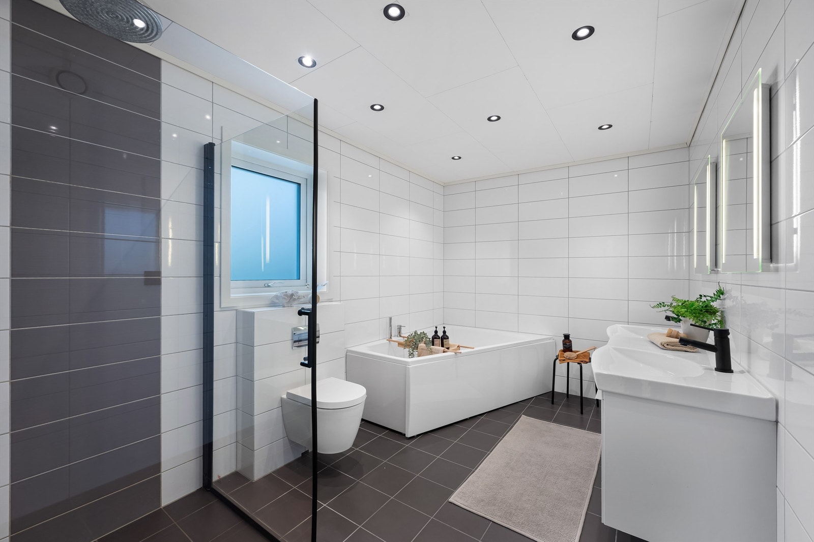 Her har du det meste du trenger for velvære med både dusj, badekar og dobbel servant. her er også god belysning fra spotter i taket Galleribilde