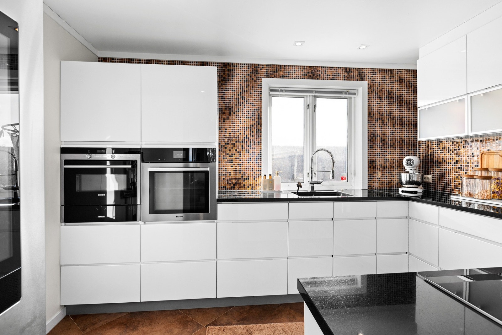 Benkeplaten er den delen av kjøkkenet du bruker og sliter mest. Det er granitt benkeplate med lekre mosaikkfliser over. Galleribilde