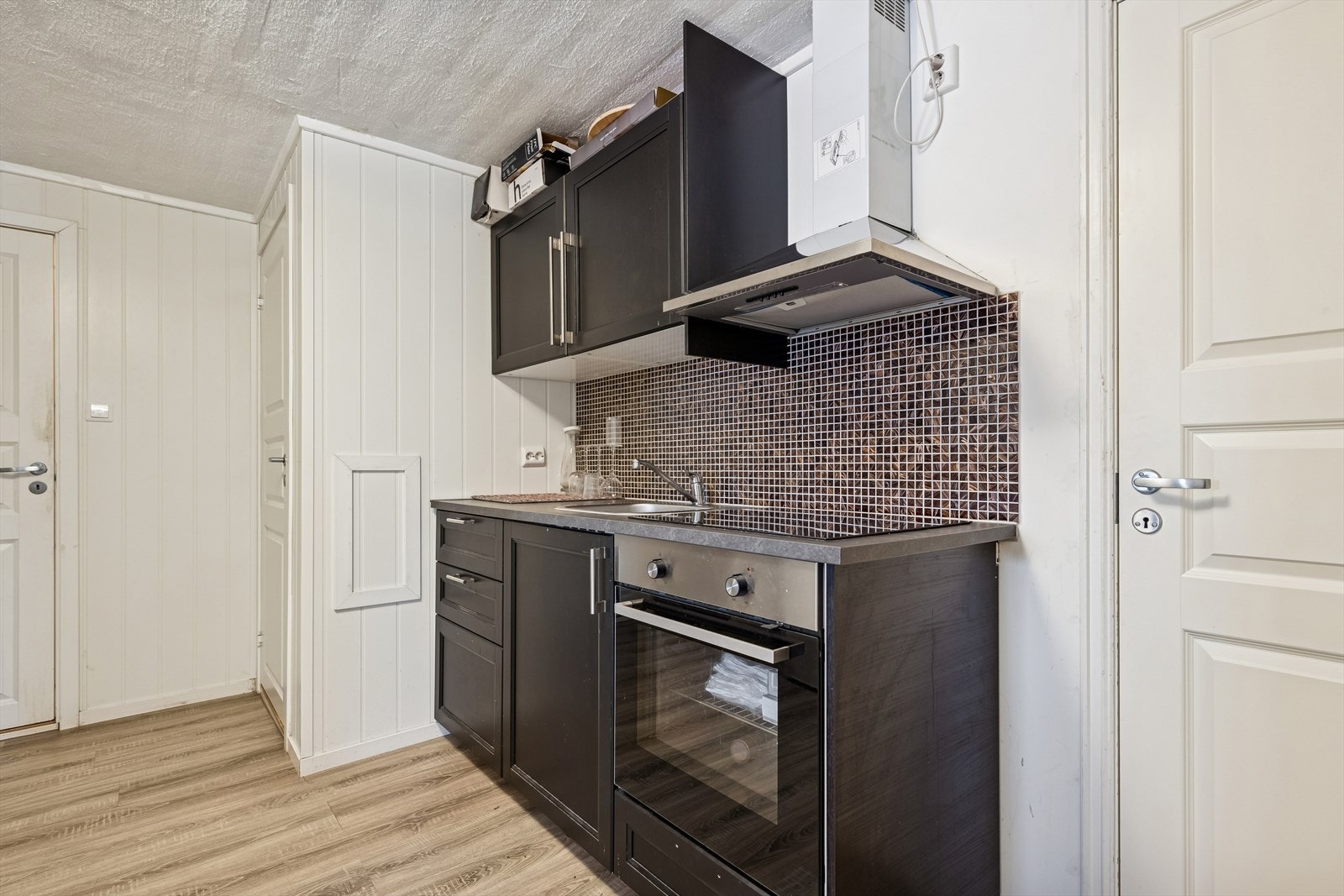 Praktisk kjøkkenkrok med integrert stekeovn, platetopp og ventilator. Galleribilde