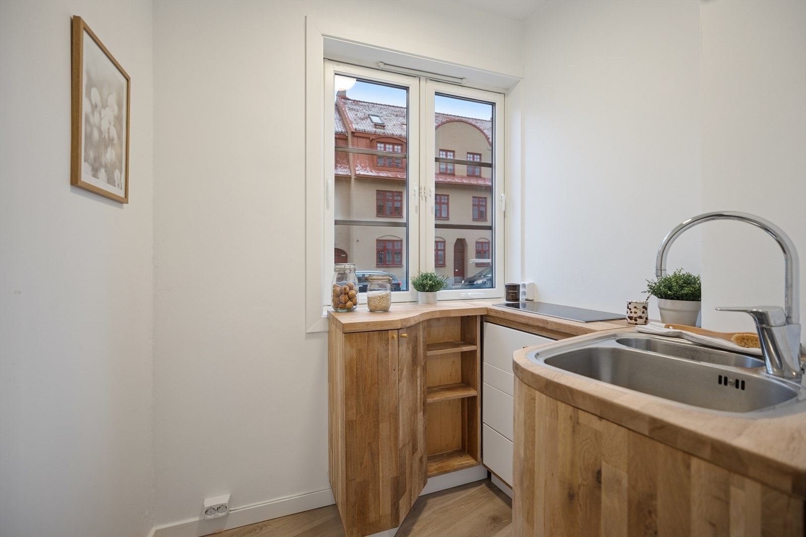 Kjøkken med hjørneløsning og vindu med utsyn mot nærliggende bebyggelse. Galleribilde