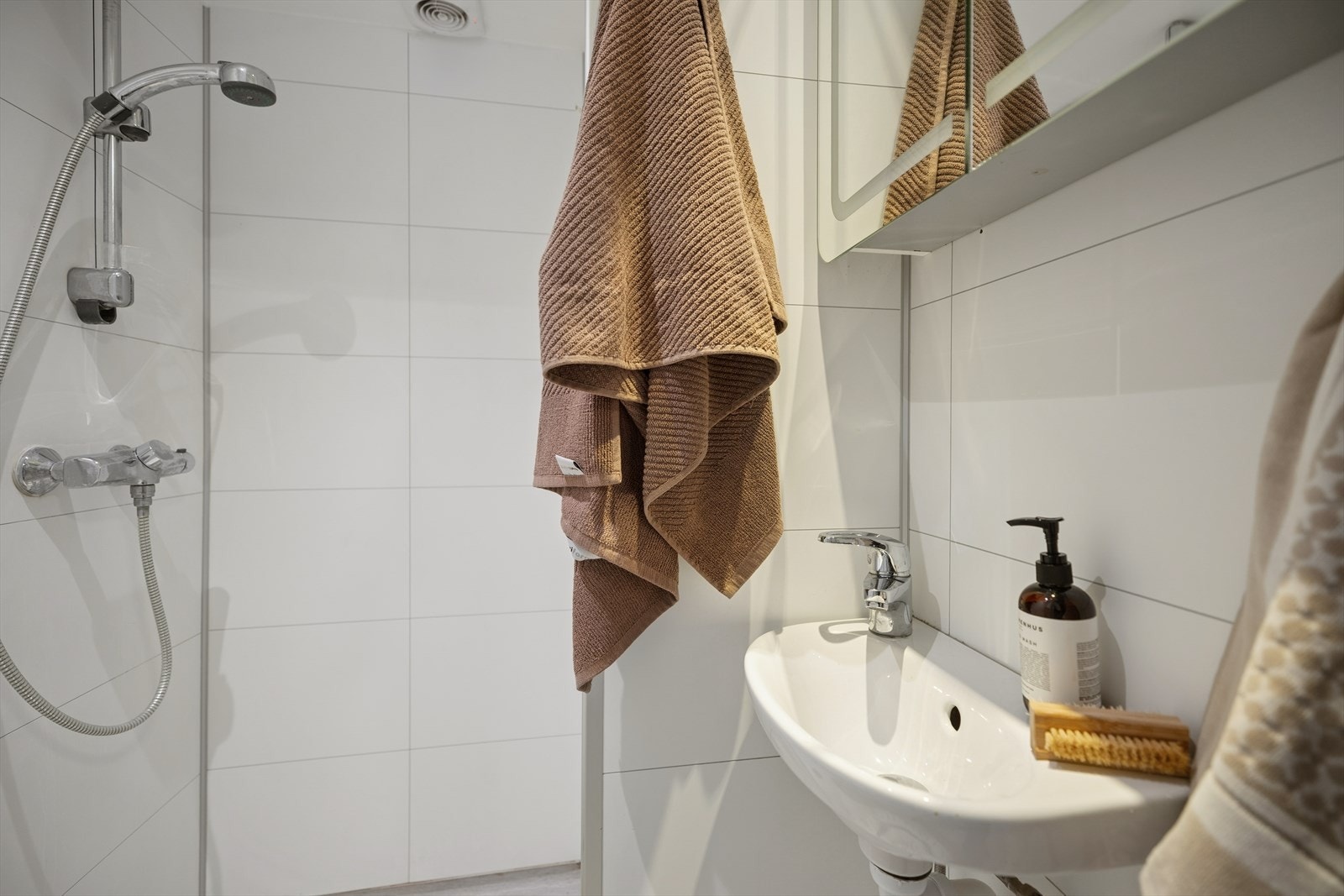 Servant med speilskap og vegghengt toalett i lyse flater. Galleribilde