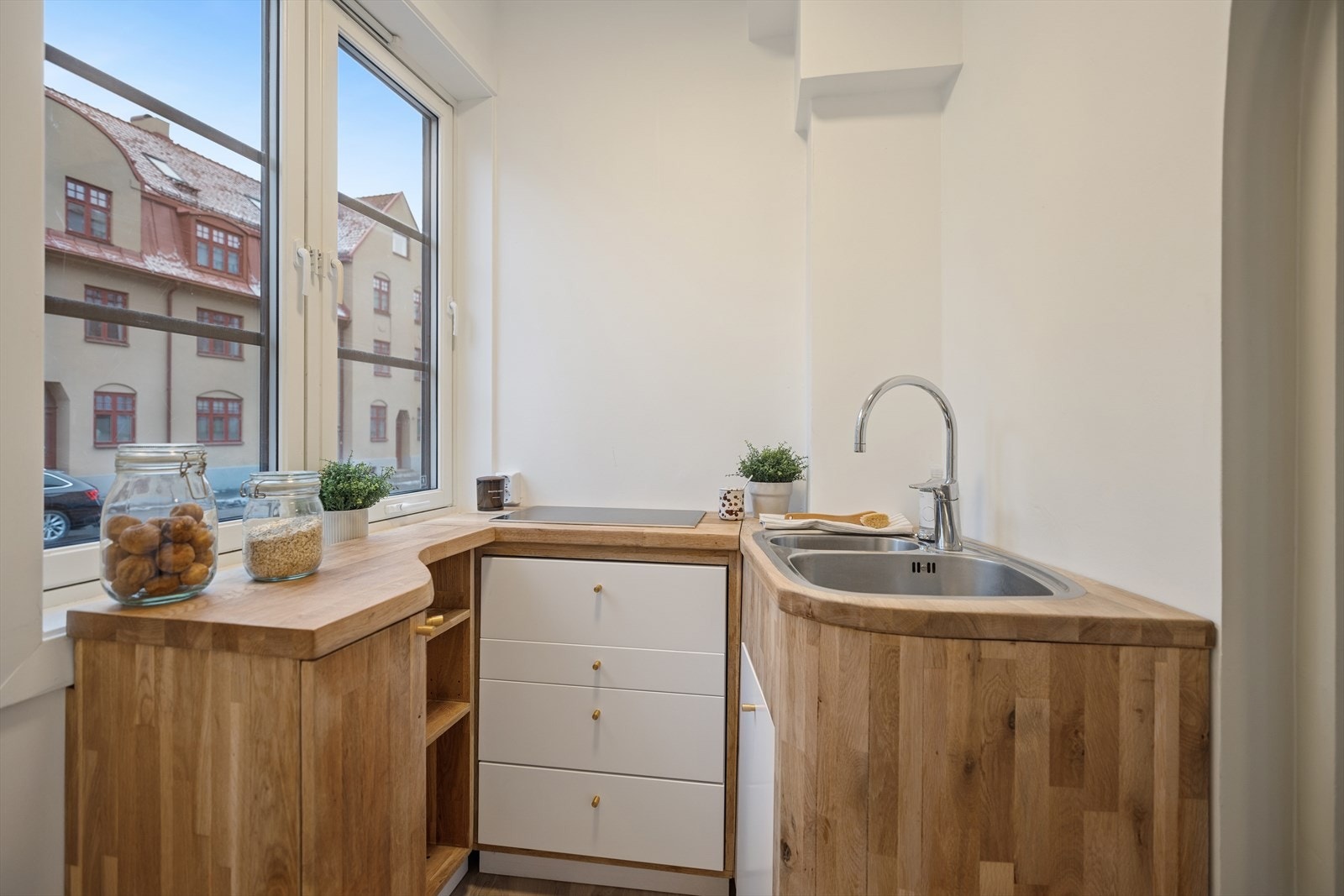 Plassbygget kjøkken med slette lakkerte fronter, heltre eikebenkeplate og integrert koketopp. Galleribilde