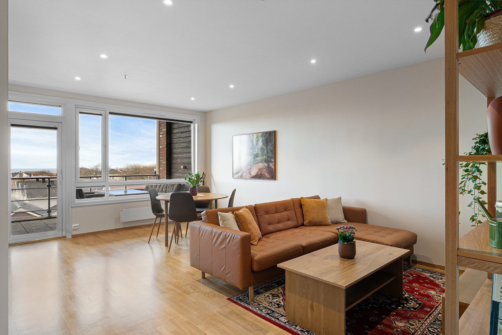 Stue og kjøkken i åpen løsning. Det er utgang til solrik balkog Galleribilde