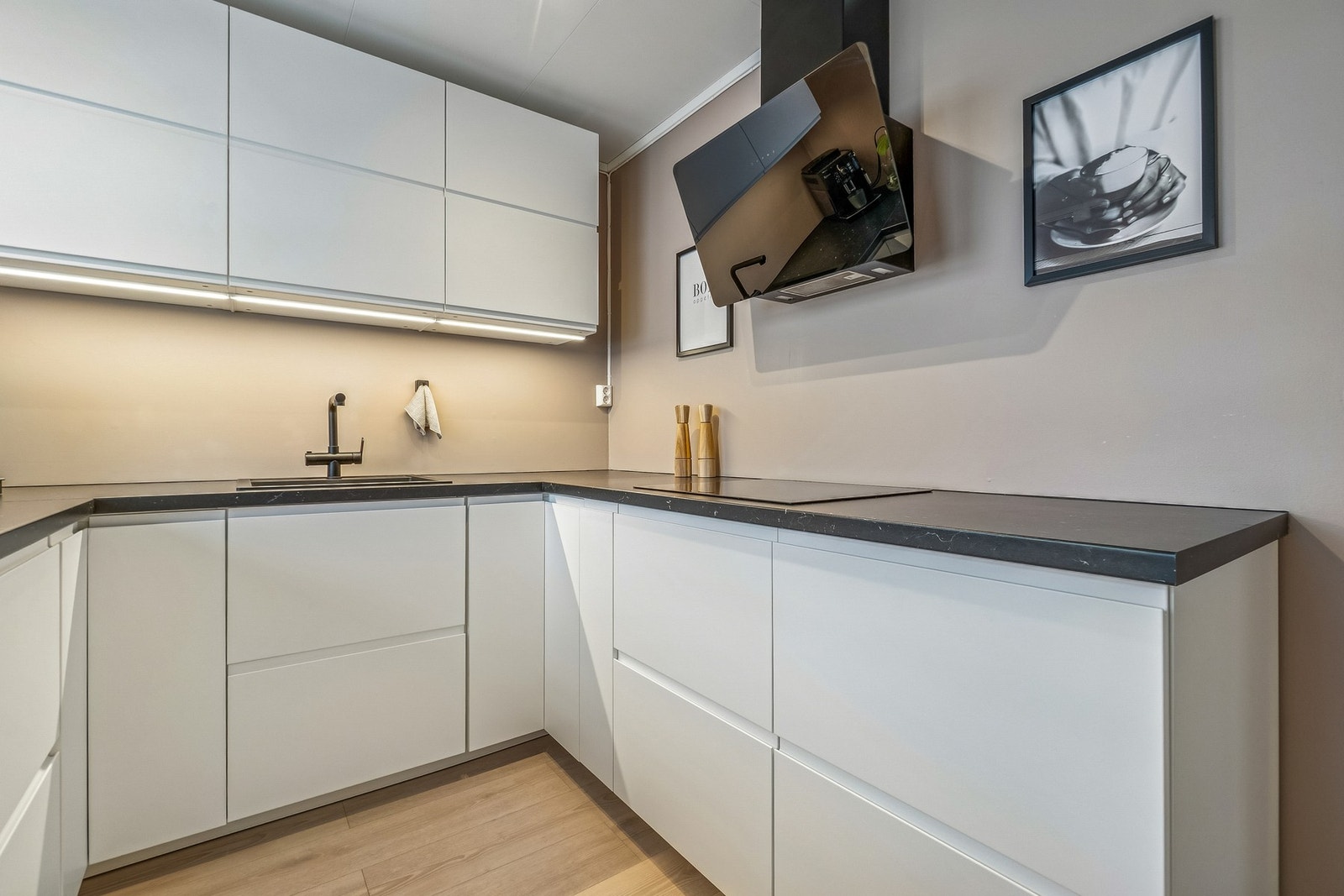 Innredningen er tidløs med hvite, håndtaksfrie fronter, og den mørke benkeplaten skaper en fin kontrast. Galleribilde