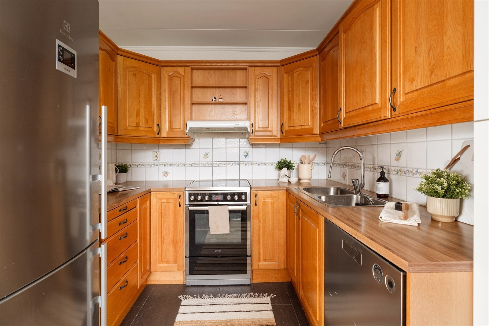 Det er frittstående oppvaskmaskin, komfyr og kjøl/frys. Galleribilde