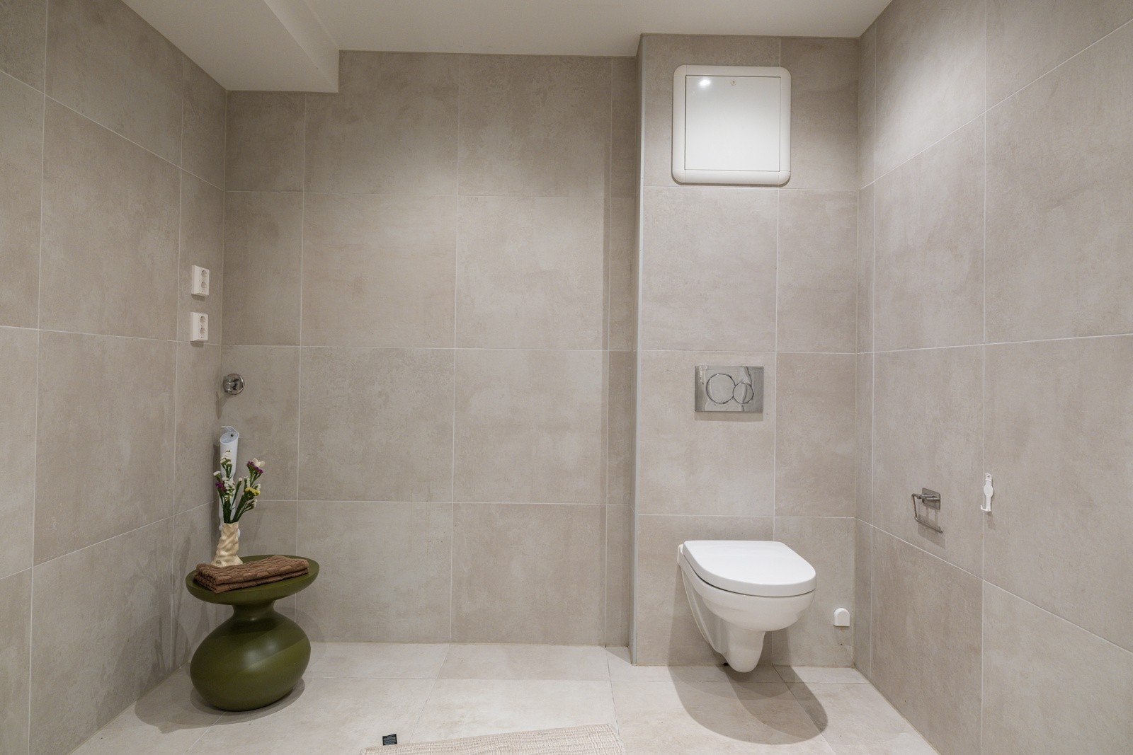 Moderne baderomsinnredning med skuffer og heldekkende servant, speil med belysning over. Baderommet er også utstyrt med dusjhjørne med innfellbare glassdører og vegghengt toalett. I hjørnet er det plass og opplegg for vaskemaskin. Galleribilde