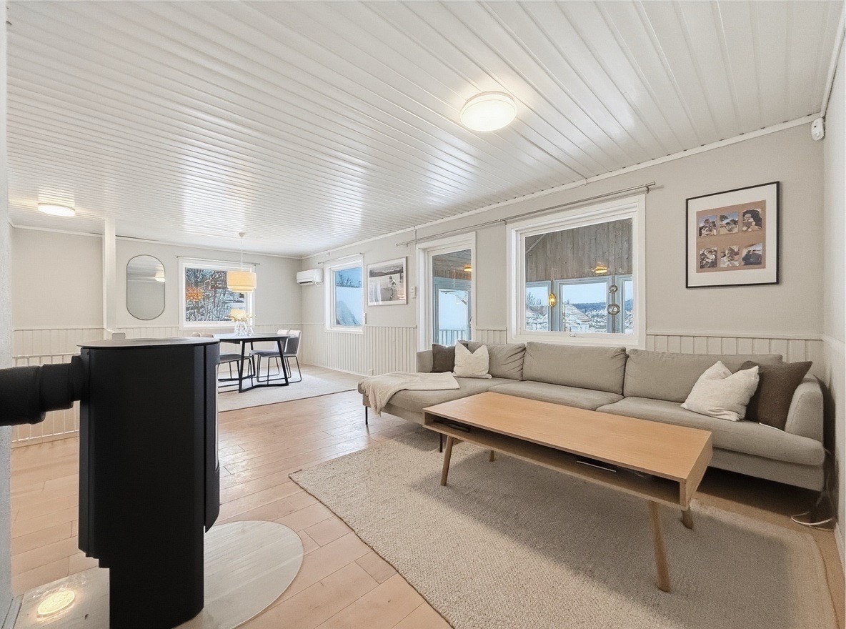 Lys stue med store vindusflater, vedovn og god plass til sofagruppe Galleribilde