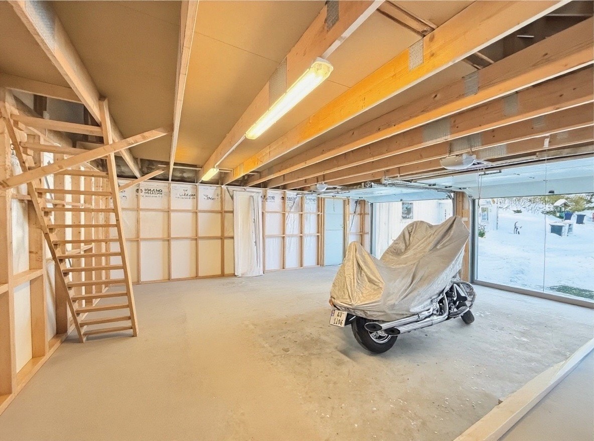 Garasjeinteriør med trapp opp til loft (loftet medfølger ikke i leien) og romslig gulvflate Galleribilde