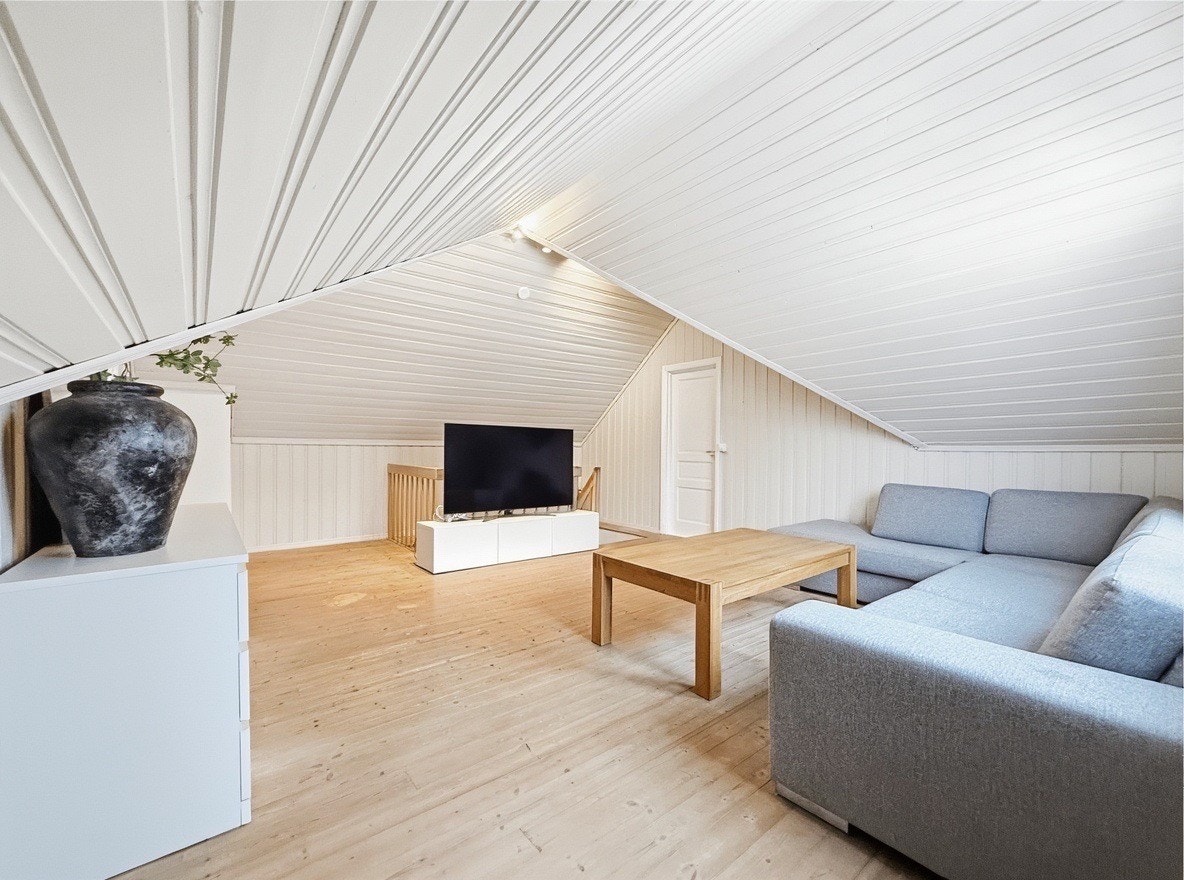 Loftstue med skråtak, sofa og store vinduer Galleribilde