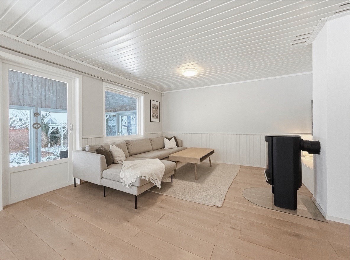 Stuen har åpen løsning mot spiseplassen og store vindusflater mot hagen Galleribilde