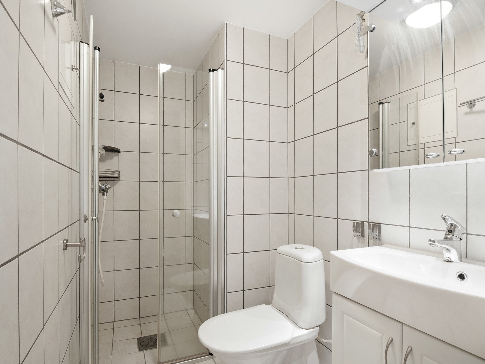 Baderommet er flislagt, og har dusjnisje med glassdør Galleribilde