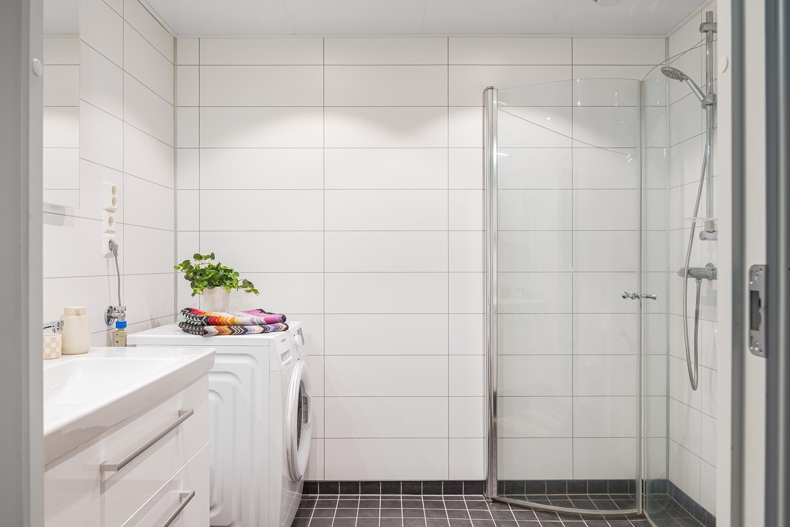 Leiligheten har et flott bad med flislagte gulv og baderomsplater på vegger. Moderne innredning med heldekkende servant nedfelt i innredning, belyst speil, dusjhørne med innfellbare dører, vegghengt toalett og opplegg for vaskemaskin. Galleribilde