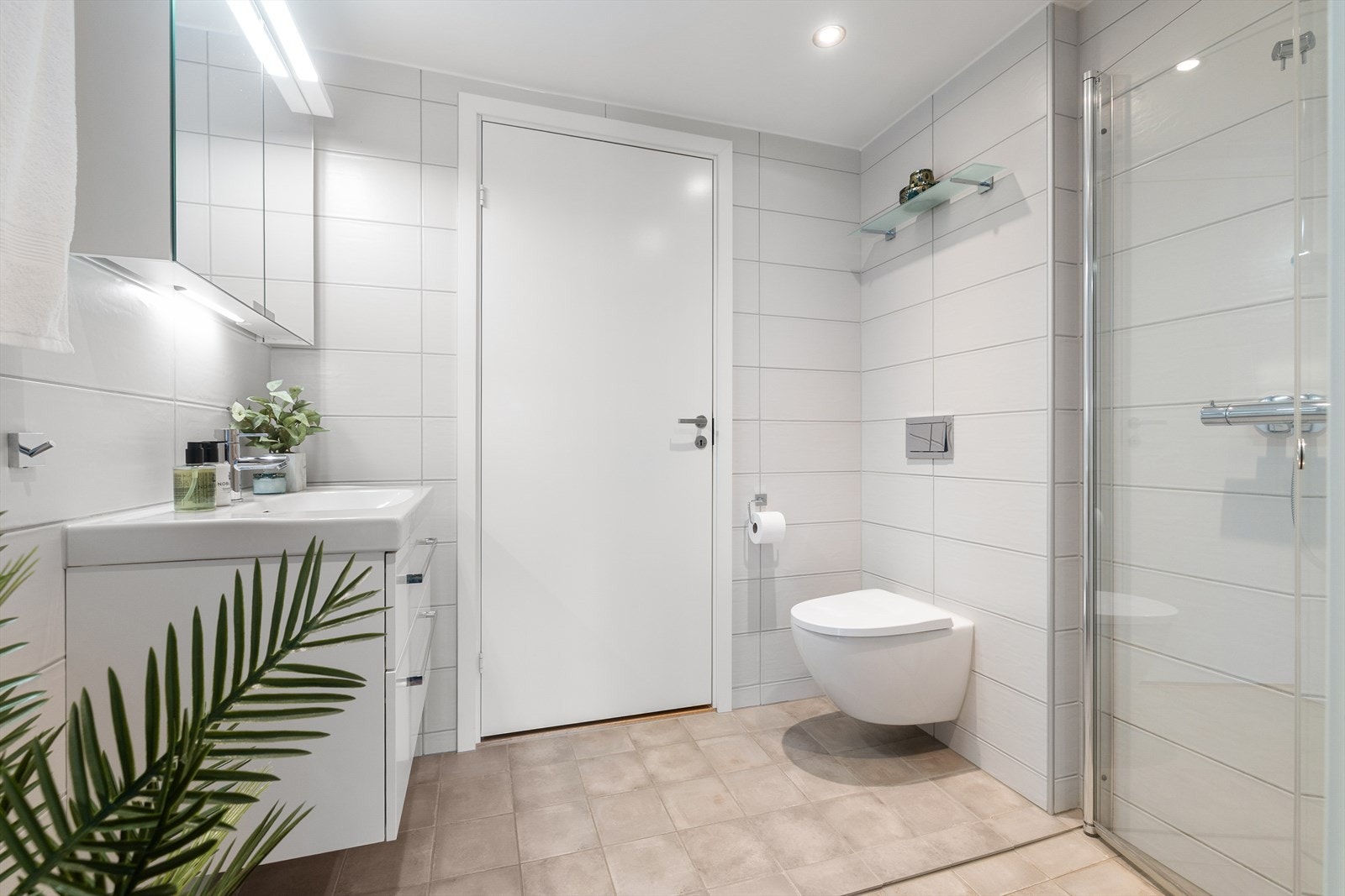 Badet er kledd med 60x20 cm fliser på vegger samt 20x20 cm fliser på gulv med varmekabler. Taket er malt og det er montert dimbare spotter i tak samt belysning over speilskap som lyskilde. Galleribilde