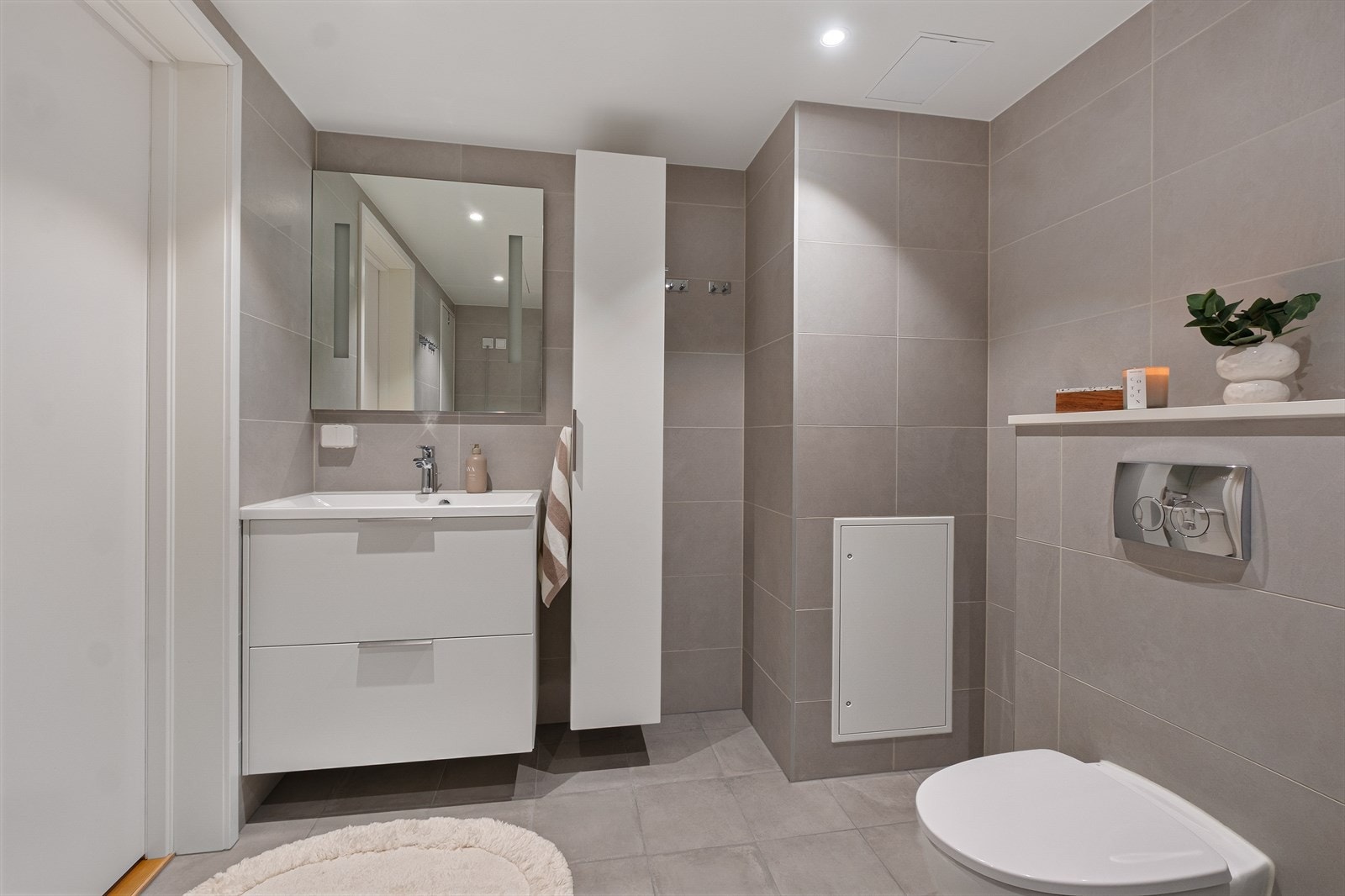 Badet er innredet med nedfelt servant, veggmontert toalett og opplegg for vaskemaskin. Galleribilde