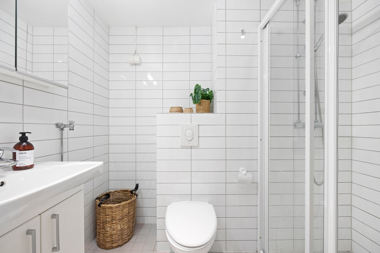 Baderommet har dusjhjørne, servantskap, veggskap med speilfronter, vegghengt wc og opplegg for vaskemaskin. Galleribilde