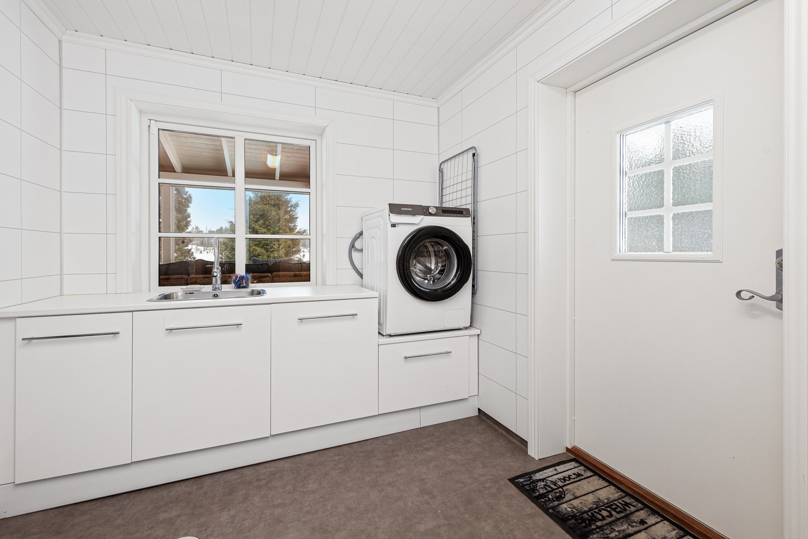 Praktisk med et stort vaskerom med egen inngang. Vinyl på gulv og våtromsplater på veggene. Hvor glatt innredning med benkeplate med nedfelt vask. Galleribilde