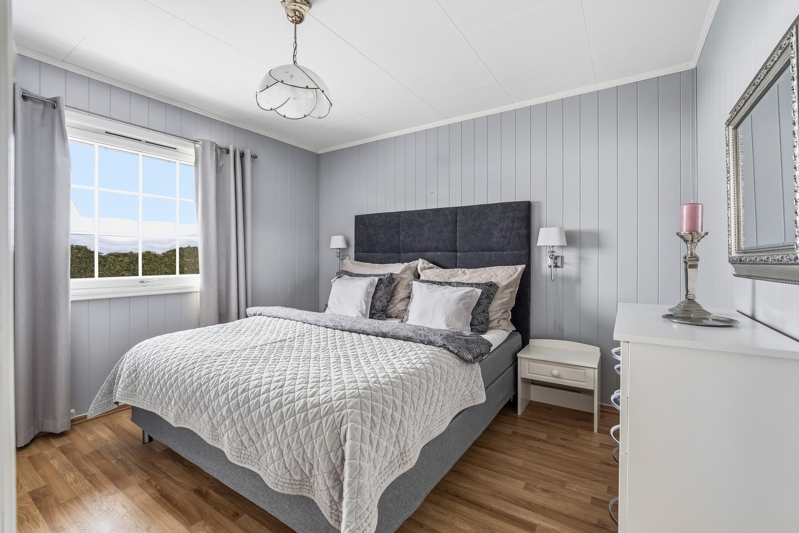 Hovedsoverommet har malte veggflater, parkett på gulv og et stort vindu som gir godt med naturlig lys. Galleribilde