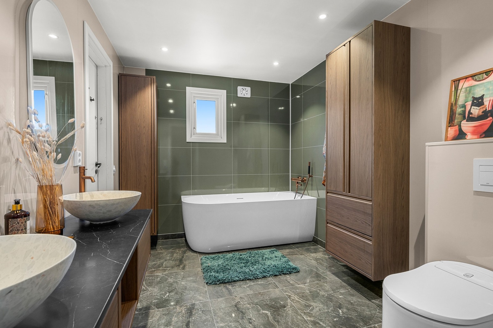 Rommet har behagelig varme i gulvet, badekar og godt med lagringsplass i skap i samme pene utførelse som servantbenken med to servanter. Galleribilde