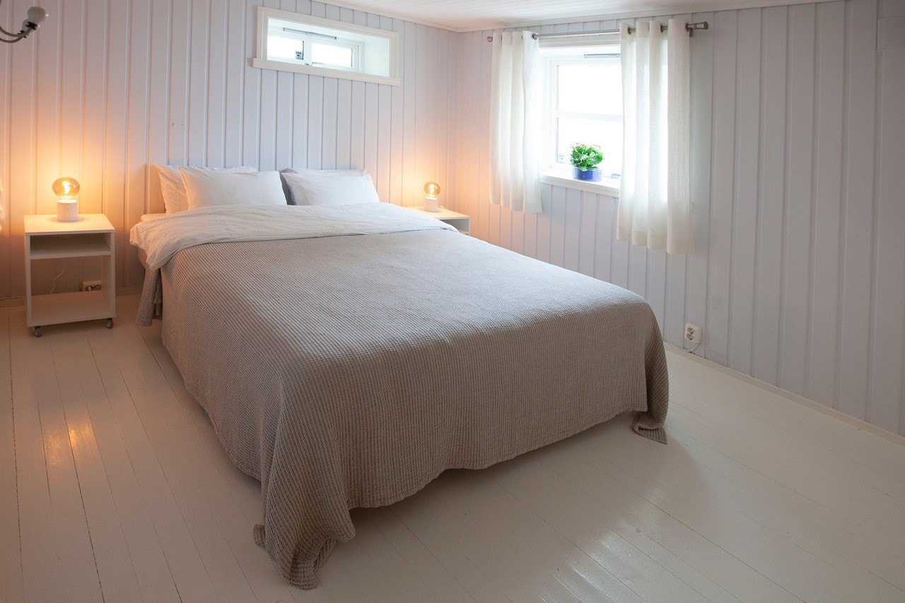 Lysmalt soverom - inneholder dobbeltseng, nattbord og klesskap. Galleribilde