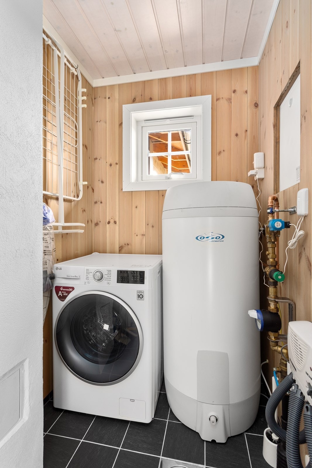 Teknisk rom/vaskerom har panel- og tømmervegger, samt panel i taket. Gulvet er flislagt, og rommet har opplegg for vaskemaskin. Galleribilde