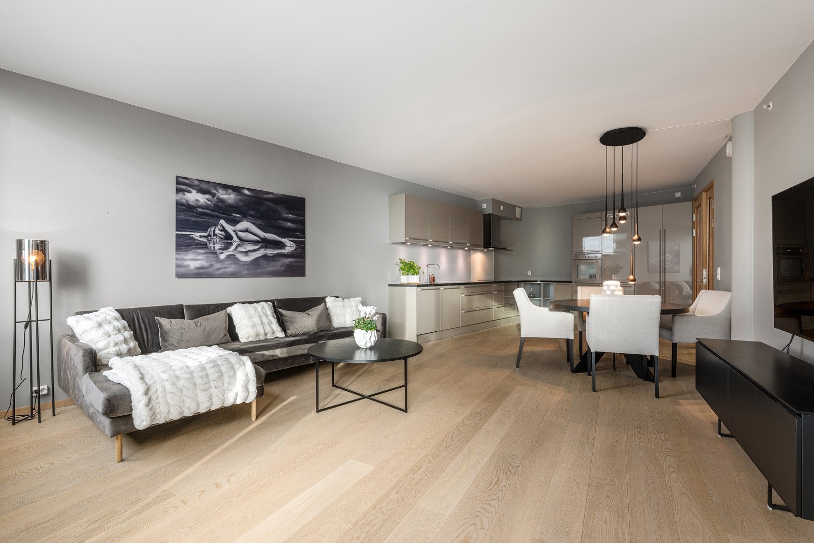 Stor stue med åpen kjøkkenløsning, store vindusflater og god plass til spisestue og sittegruppe. Rommet er på over 40 m² og innbyr til sosiale sammenkomster Galleribilde