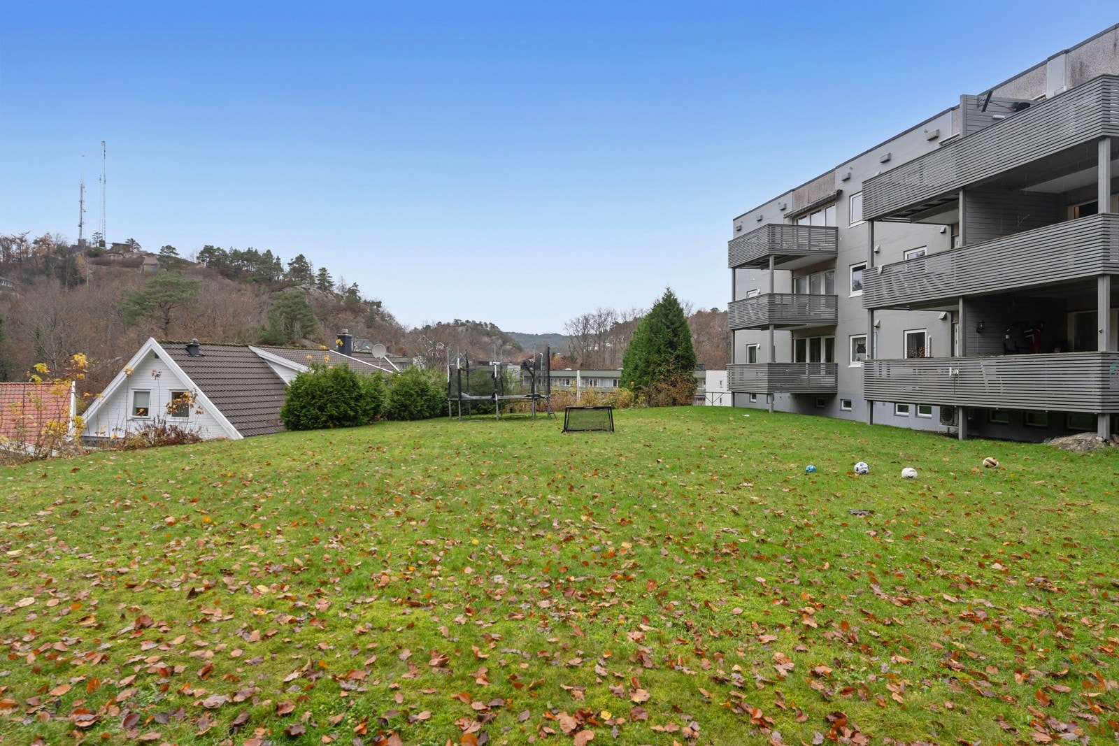 Boligblokken har et solrikt fellesområde med plen som kan brukes til ulike aktiviteter. Galleribilde