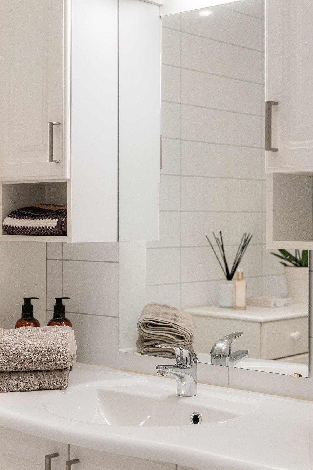 Baderomsinnredningen har hvite, profilerte fronter og består av en heldekkende servant på en skapseksjon, et høyskap, to veggskap og et speil med belysning. Galleribilde