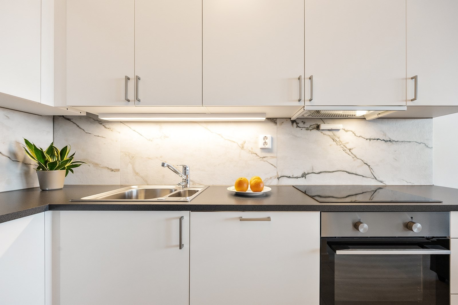 Kjøkkeninnredning med slette, hvite fronter og mørk laminatbenkeplate. Galleribilde