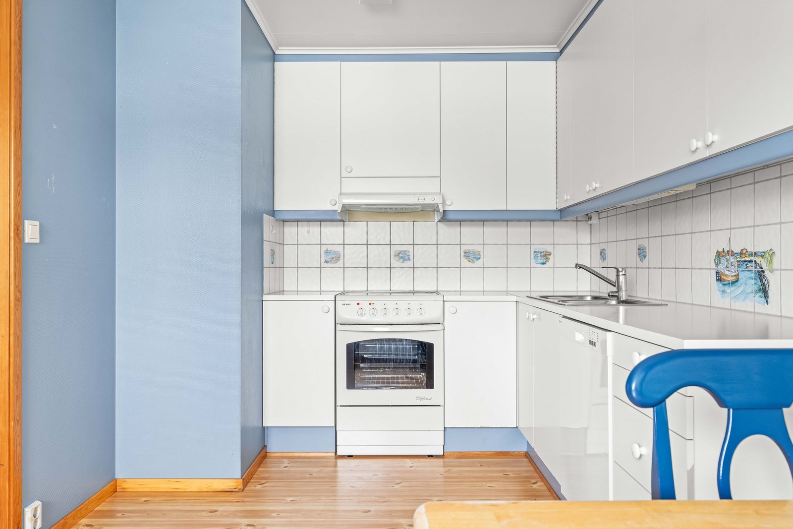 Flislagt felt mellom kjøkkenbenk og overskap, med praktisk benkeskapsbelysning og stikkontakter plassert under overskap. Galleribilde