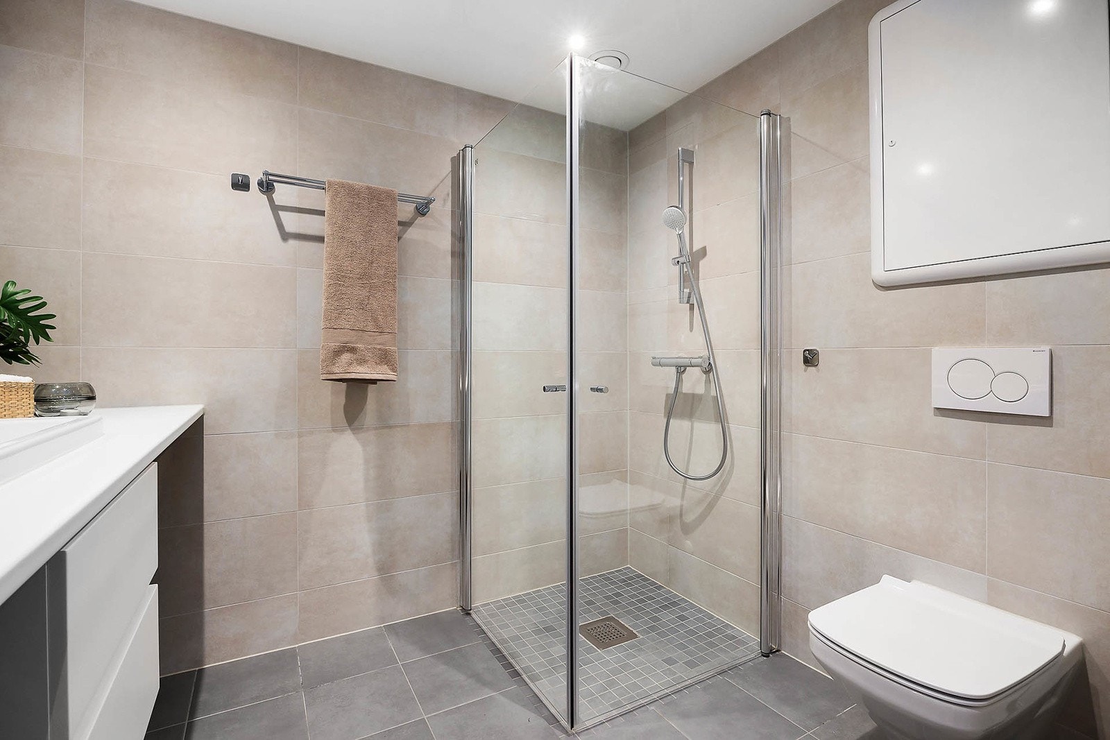 Badet er utstyrt med dusjhjørne med svingbare glassdører, servant med hvite skuffeseksjon, speil med belysning, samt vegghengt toalett. Galleribilde