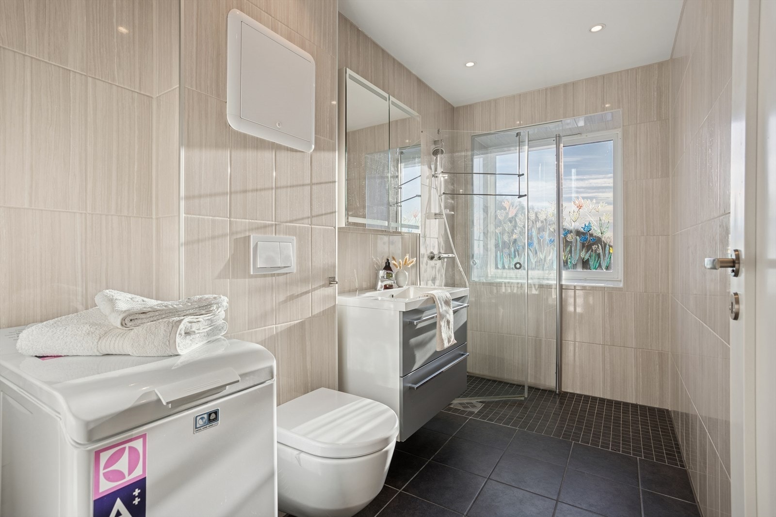 Badet fremstår moderne og funksjonelt, med fliser på både gulv og vegger som gir et helhetlig og stilrent uttrykk. Galleribilde