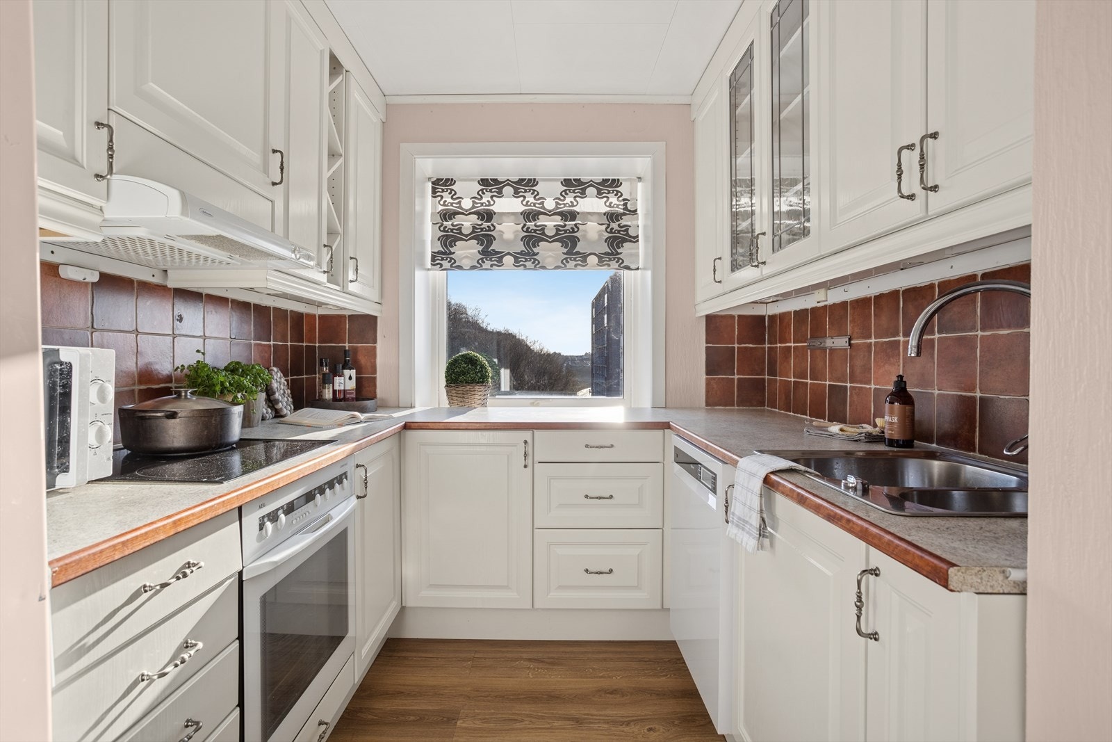 Kjøkkenet er utstyrt med laminert benkeplate og flislagt felt over benk for et praktisk og tidløst uttrykk. Galleribilde