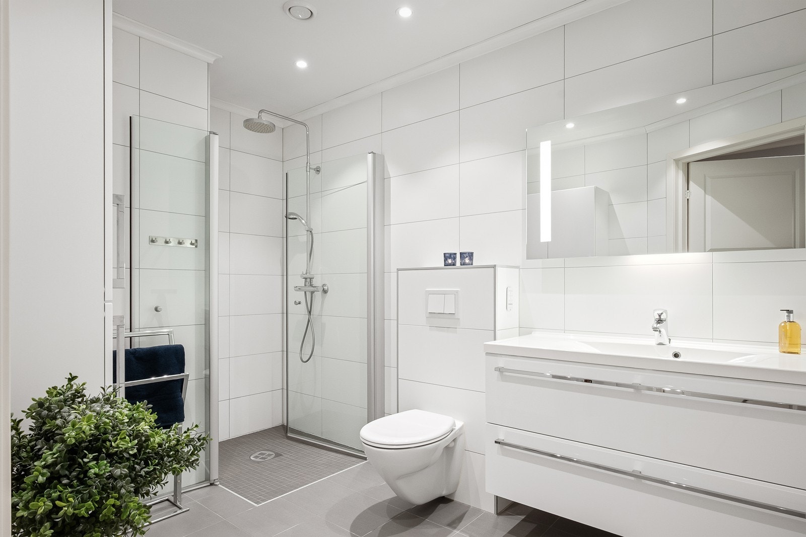 Badet er fra byggeår med flislagte overflater, gulvvarme og downlights i himling. Det er romslig dusjhjørne med både takdusj og hånddusj. Galleribilde