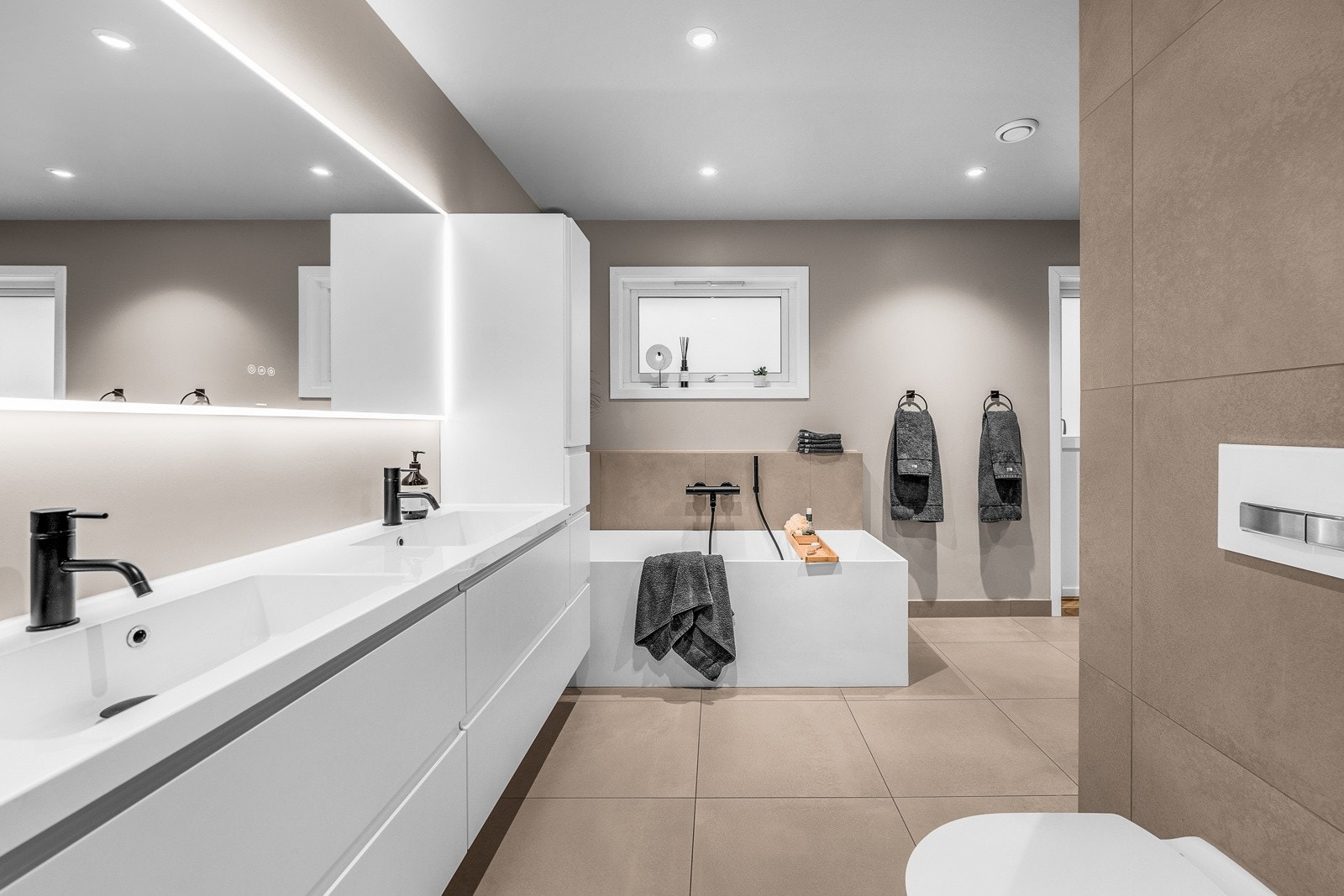 Helfliset bad med rent og moderne uttrykk, gjennomført materialvalg og god plass til komfortable hverdagsrutiner. Galleribilde