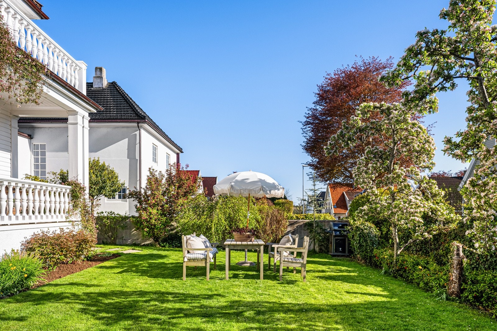 Tomten er parkmessig opparbeidet med gressplen, skiferlagte stier, fargerike prydbusker og frukttrær. Galleribilde