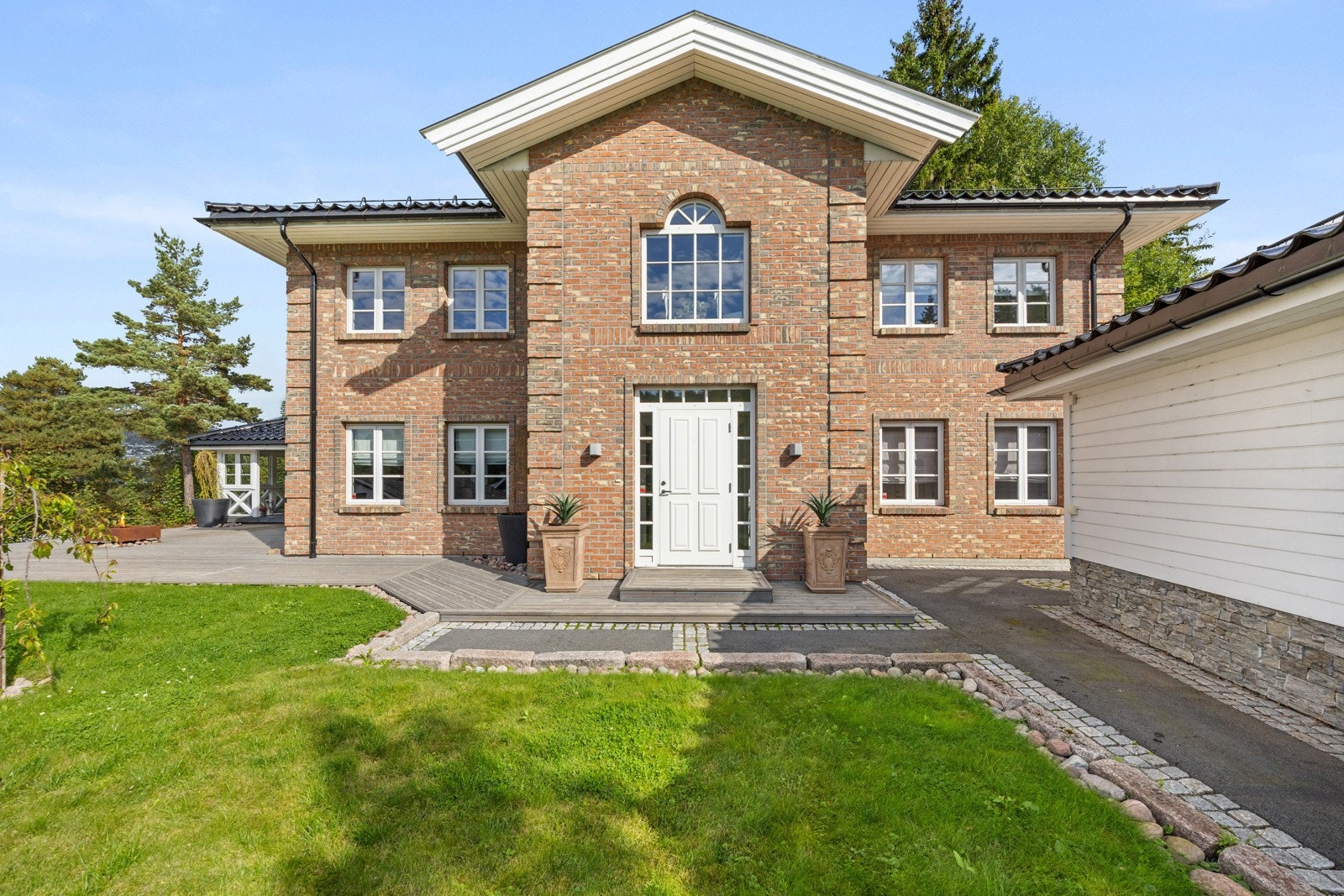 Tomten har flere soner, men likevel en helhet - asfalterte internveier med stein og stor terrasse som strekker seg fra inngangspartiet og rundt husveggen. Galleribilde