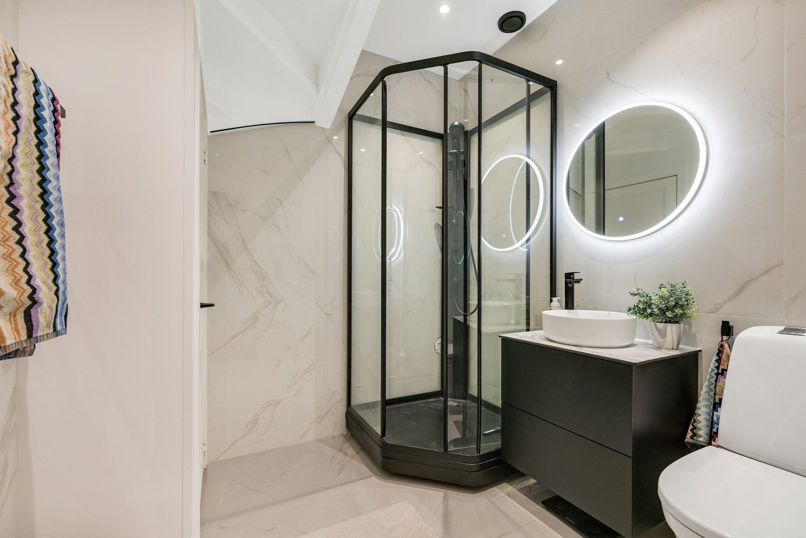 Toalettrom innredet med gulvmontert toalett, håndvask og speil over vasken. Galleribilde