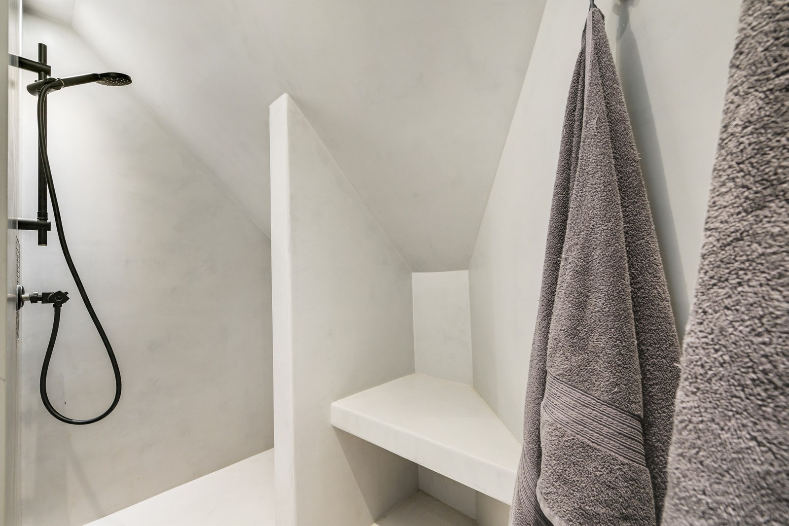 Delikat dusjrom med microsement på gulv, vegger og i tak, det er varmekabler i gulv - innredet med dusjgarnityr. Galleribilde