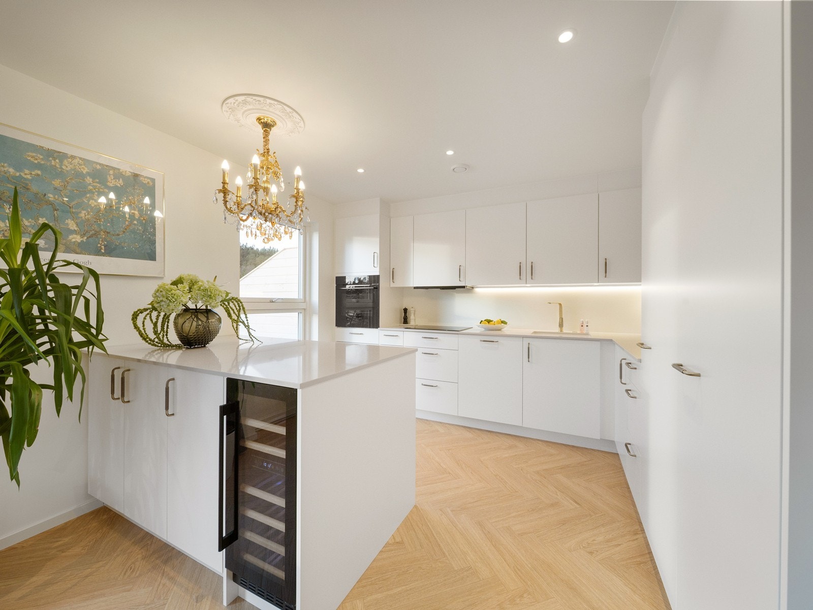 Lekkert kjøkken fra Kvik med hvite fronter, kompositt benkeplate, integrerte hvitevarer med vinskap for ekstra luksus. Galleribilde