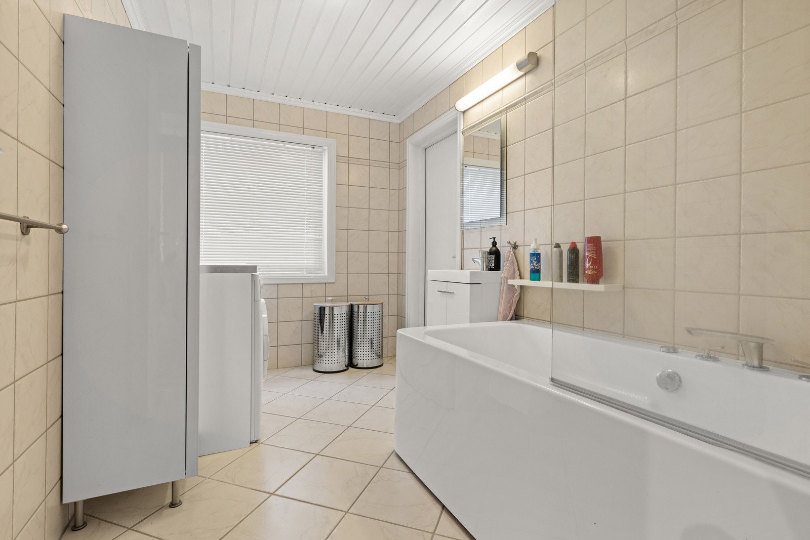 Romslig bad med flislagte overflater, badekar og servantinnredning Galleribilde