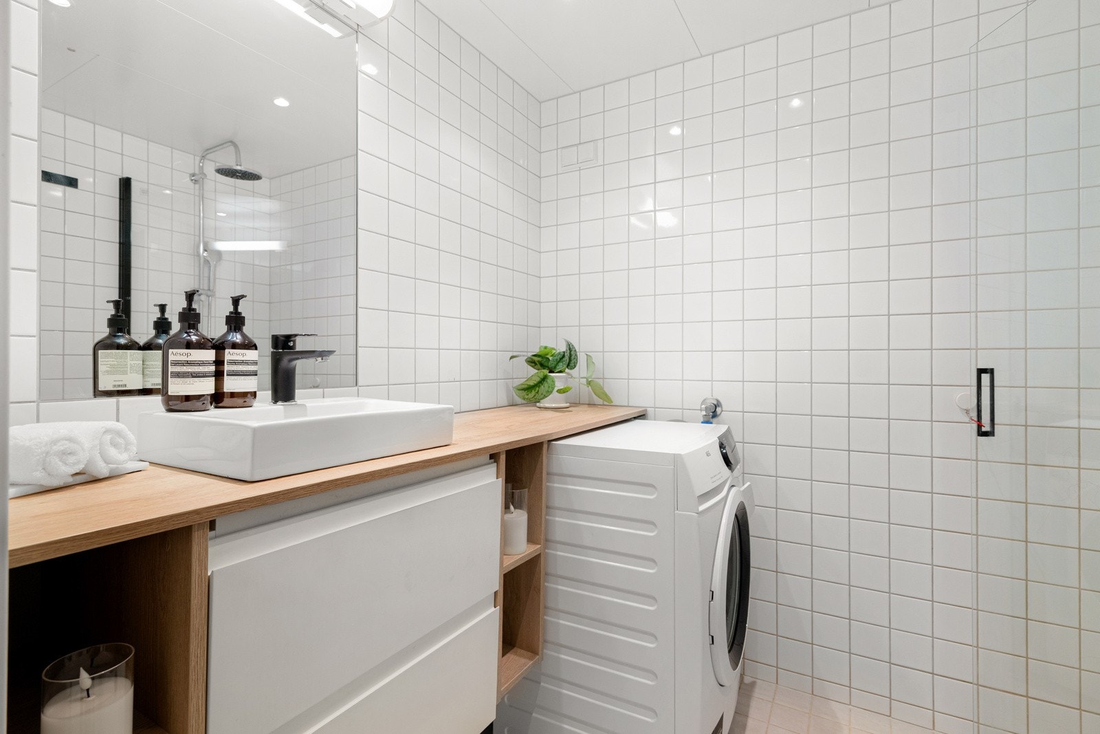 Baderommet er innredet med servant på benkeplate, kombinert med skuffer og åpne hyller som gir god oppbevaringsplass. Galleribilde