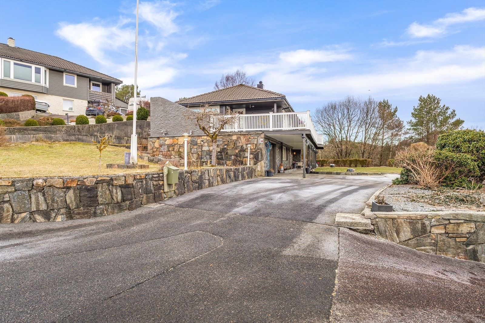 Stilfull fasade med steinmur og grønne omgivelser skaper et innbydende førsteinntrykk. Galleribilde