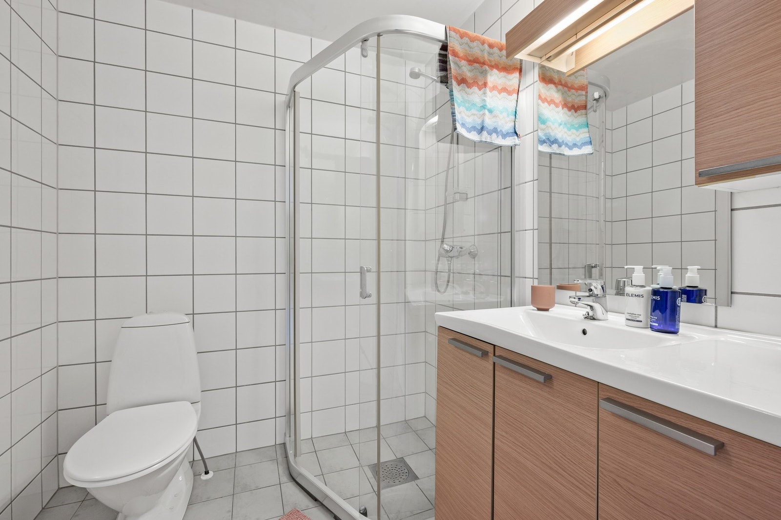 Flislagt bad med gulvvarme. Badet inneholder wc, dusjhjørne og servant med innredning. Galleribilde