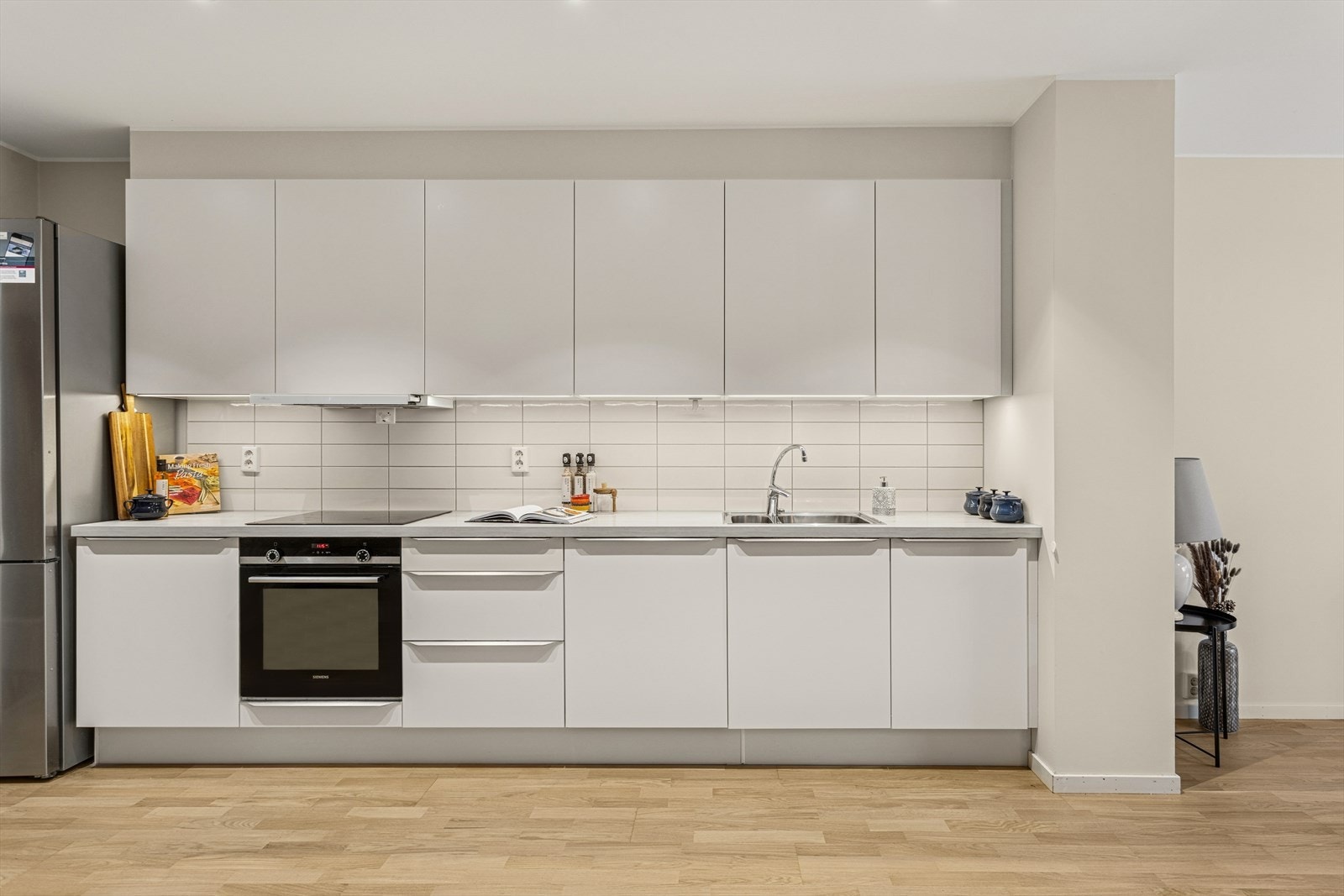 Kjøkkeninnredning fra HTH med integrerte platetopp, komfyr og oppvaskmaskin. Videre er det plass til et frittstående kjøl/fryseskap i enden. Galleribilde