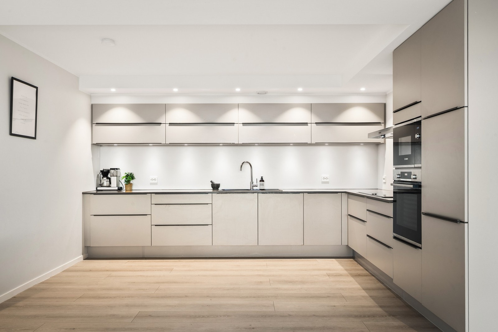 Kjøkkeninnredningen består av slette fronter, kompositt benkeplate, over benkeplaten er det benyttet malte flater, oppvaskkum og ventilator. Galleribilde